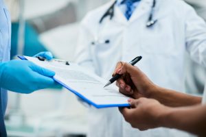 Close-up of African American woman signing paperwork during medical appointment at clinic.